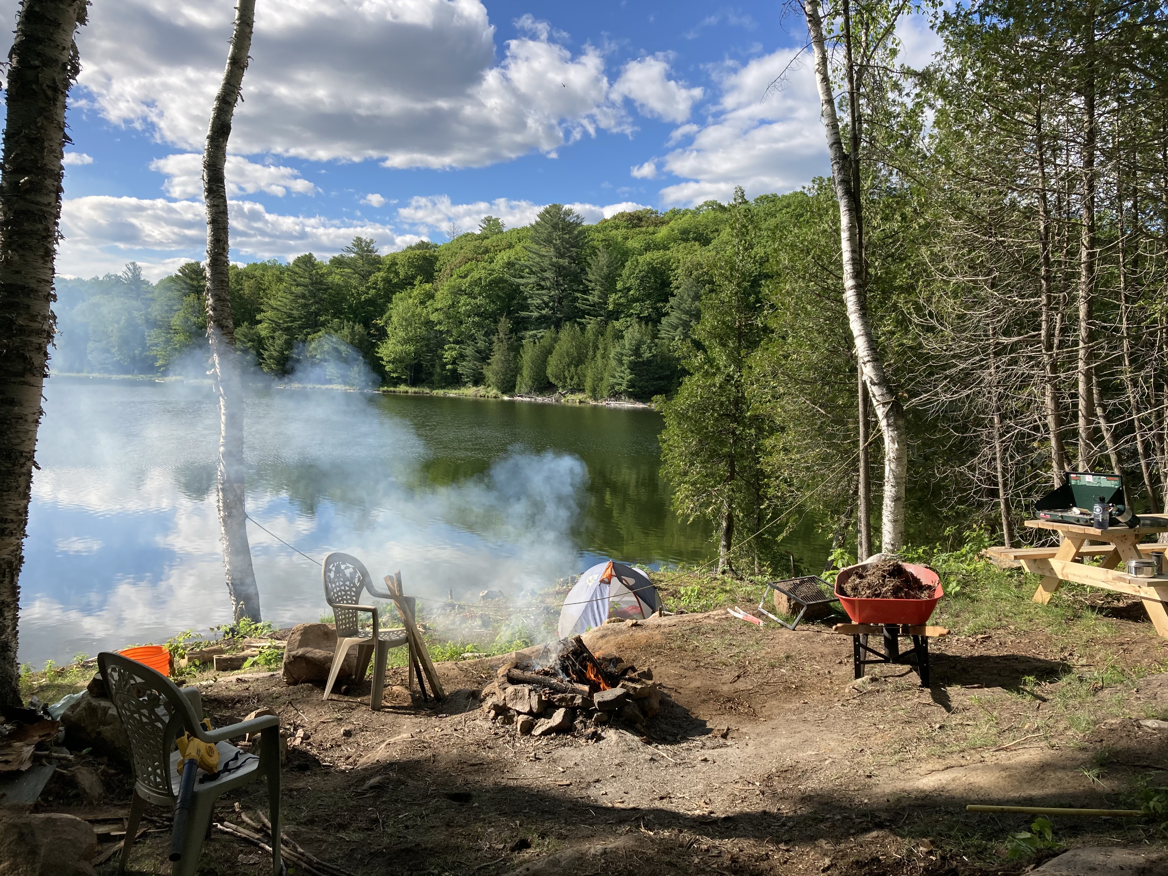 The fire pit established by the water, on top of a rocky ledge, and a new picnic table with a Coleman camp stove