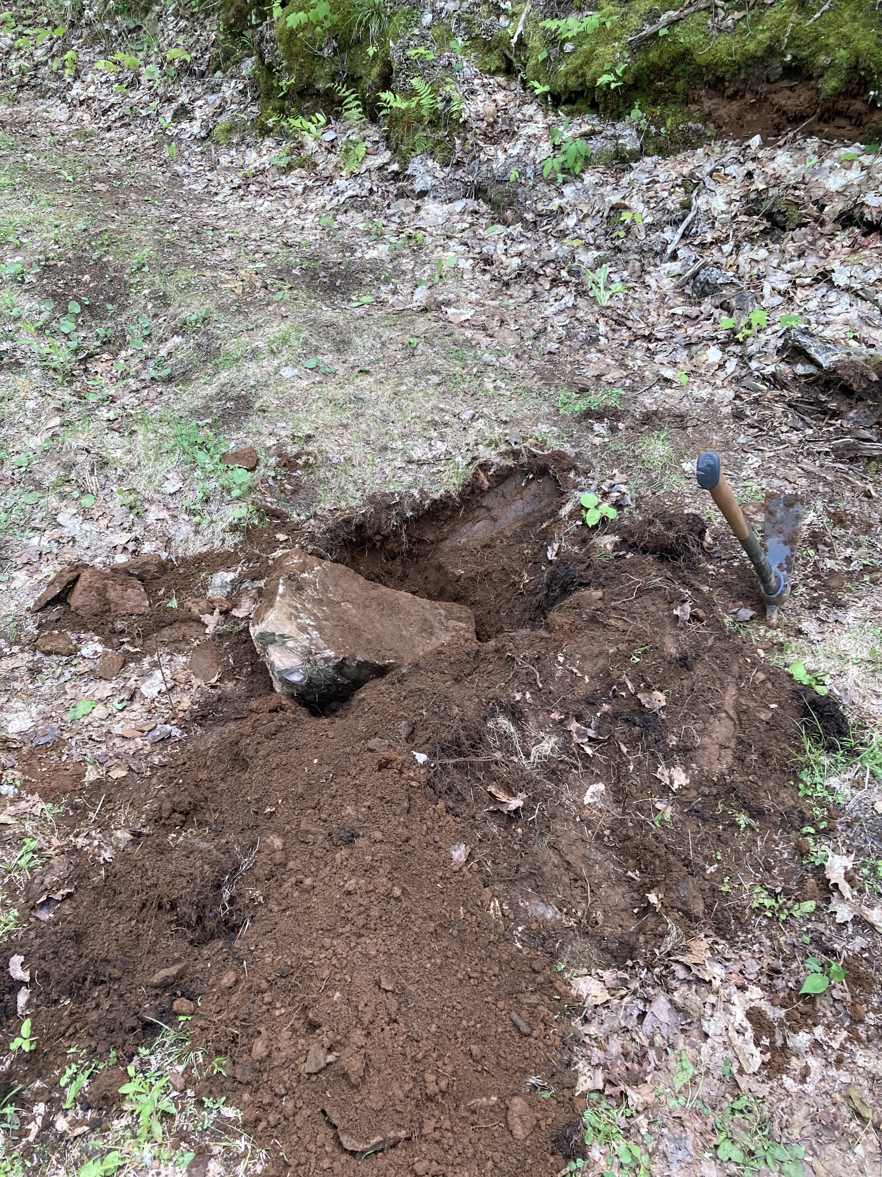 A one-foot-cubed rock and a pick axe, telling the story of plucking the rock from the ground