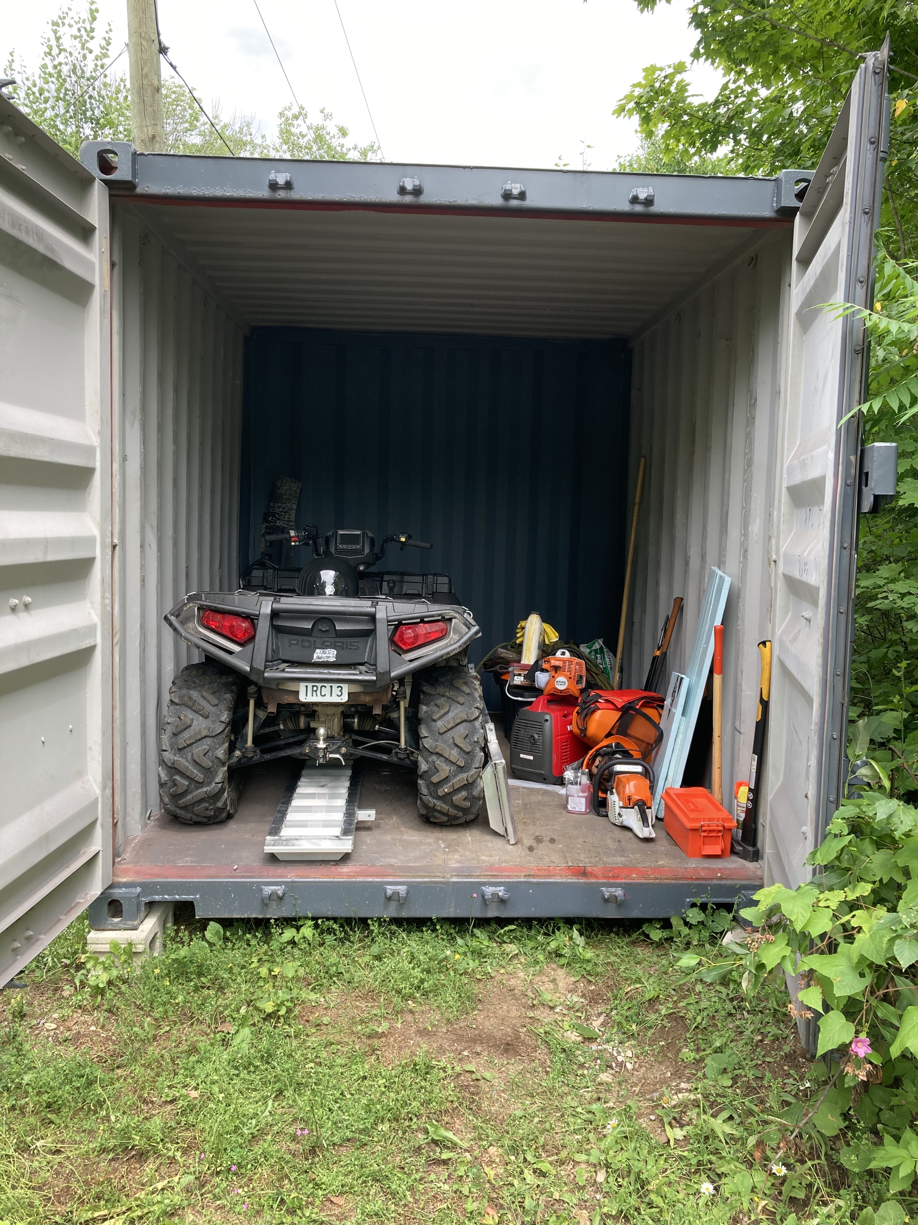 ATV nestled into the sea can beside a pile of tools on the floor