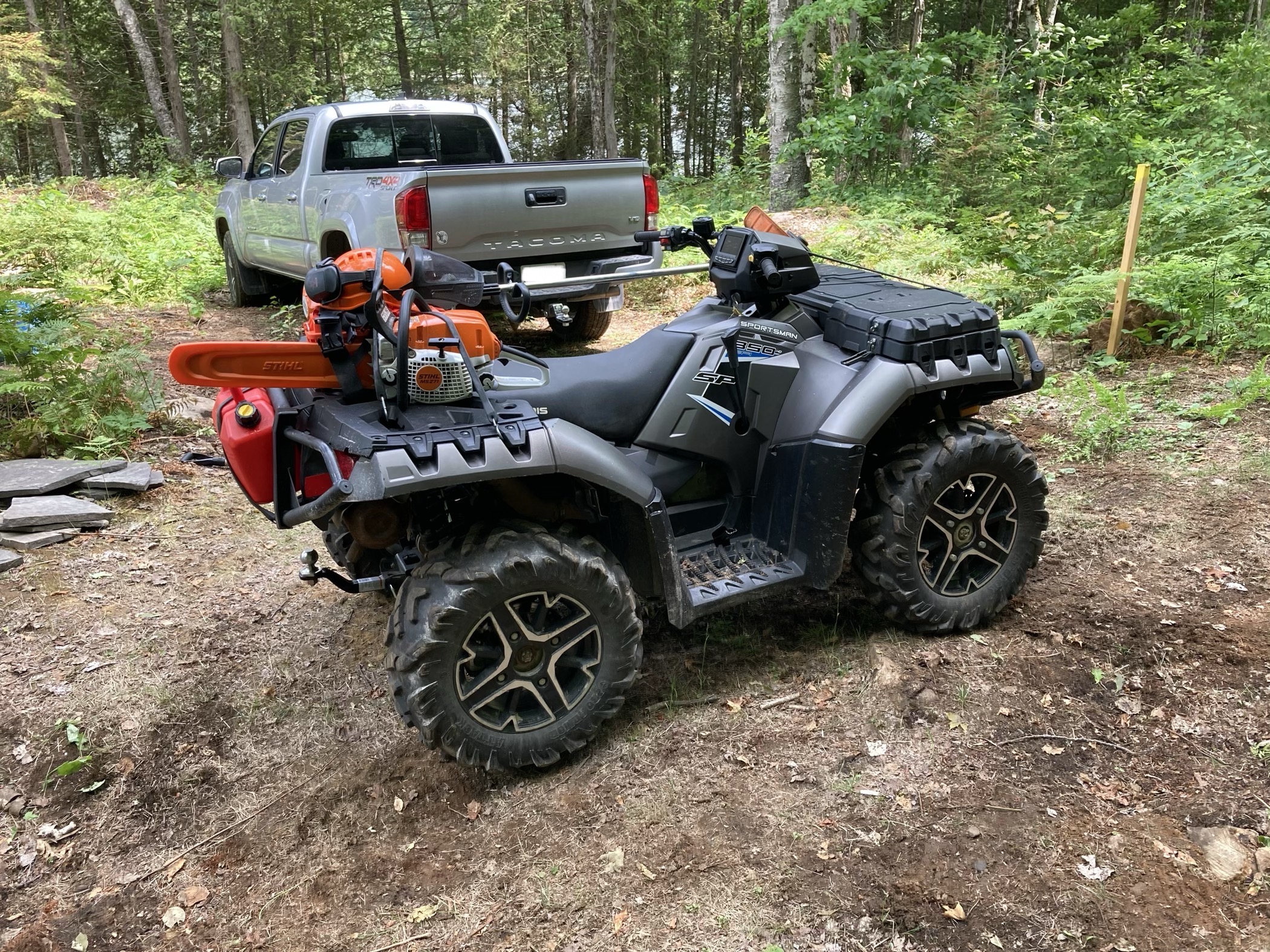 ATV in front of my Tacoma, with chainsaw, weed wacker, and accessories strapped to the back.