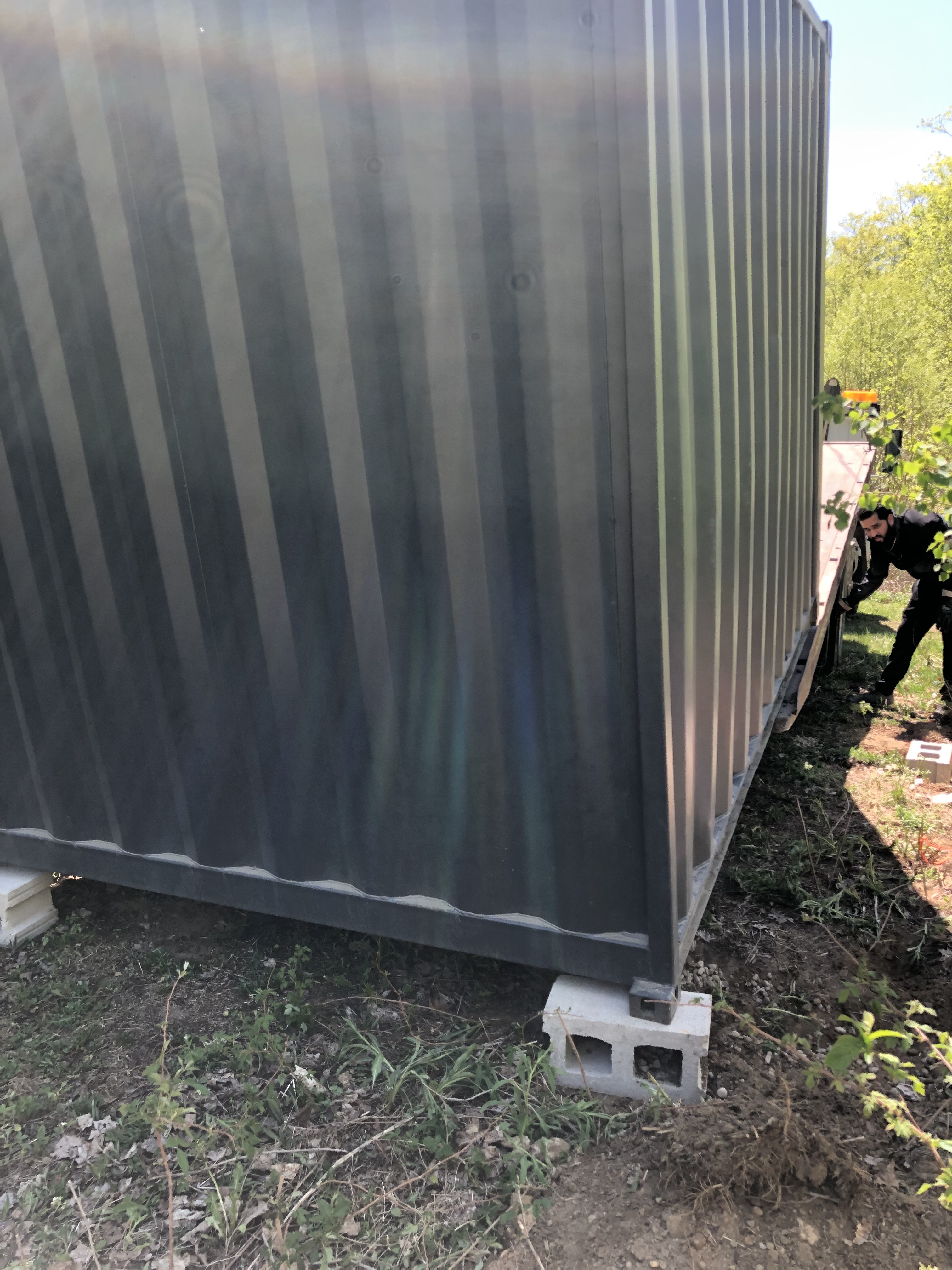 The flat bed truck, with a tipping bed, tilting the container onto two cinderblocks at the back corners. These blocks have already been moved from their original positions to account for the innaccuracy of the truck.