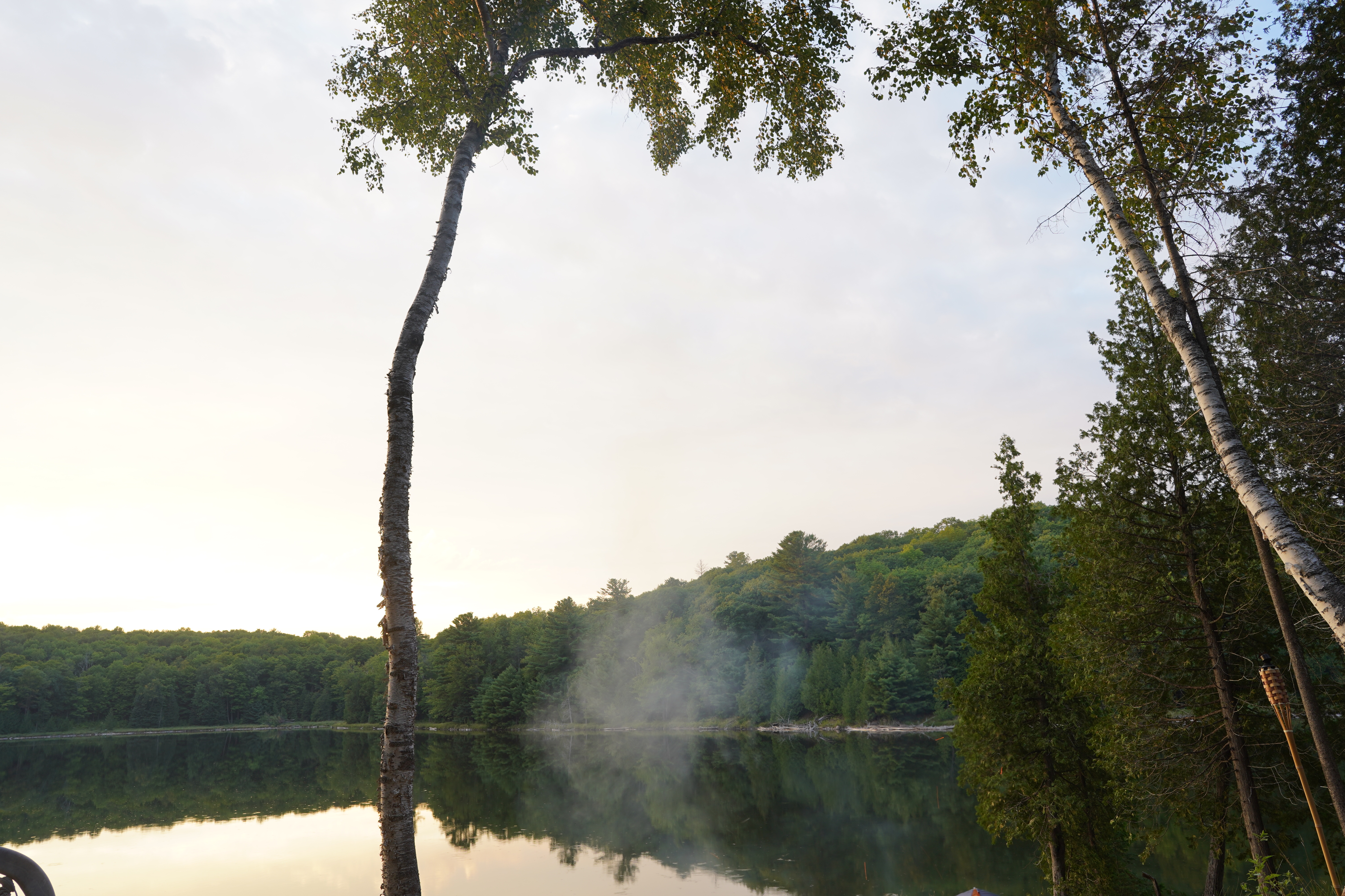 A little puff of fire smoke over the calm lake in early evening.