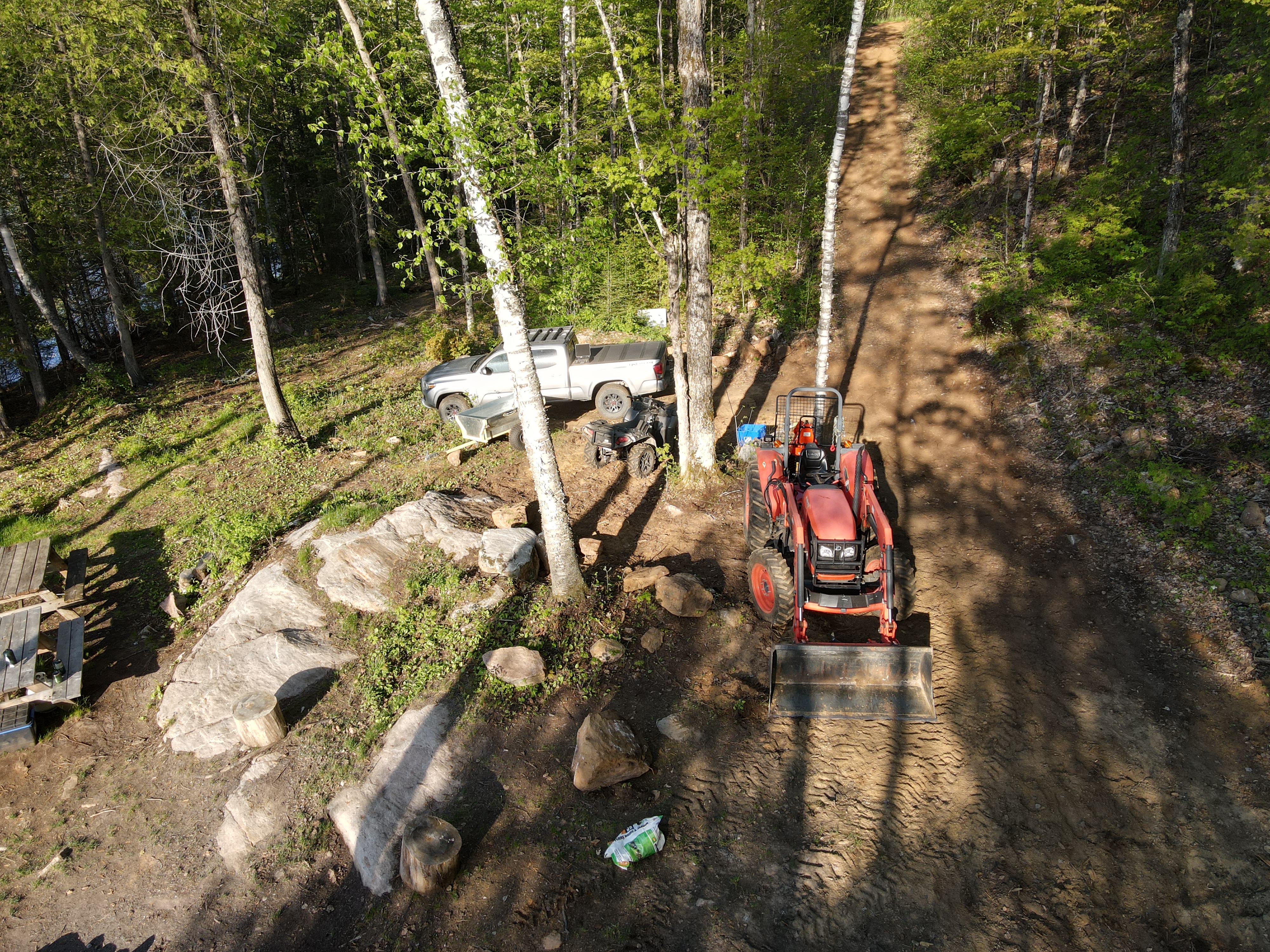A drone shot of the same turnaround area with the Tacoma, ATV, and tractor in shot.