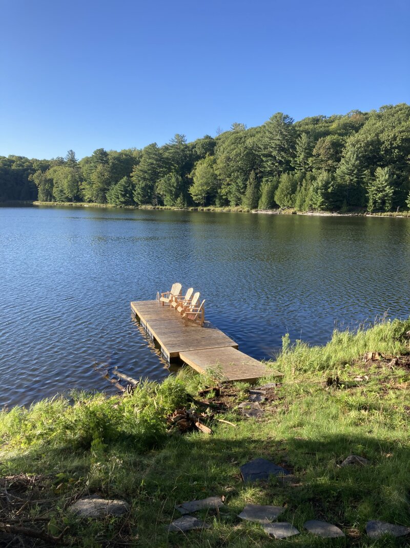Finished dock with Muskoka chairs on a blue sky day