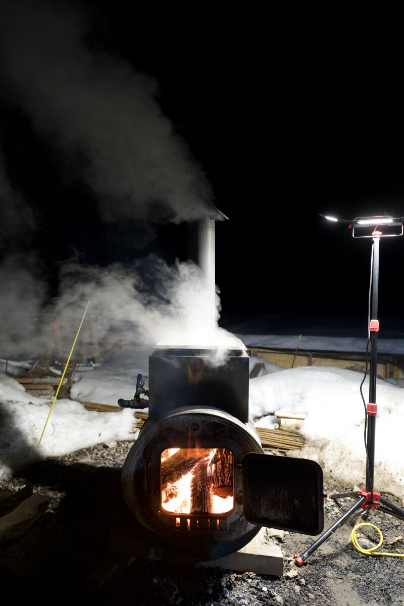 The barrel evaporator up to temperature in the evening, fire box door open with a raging fire inside