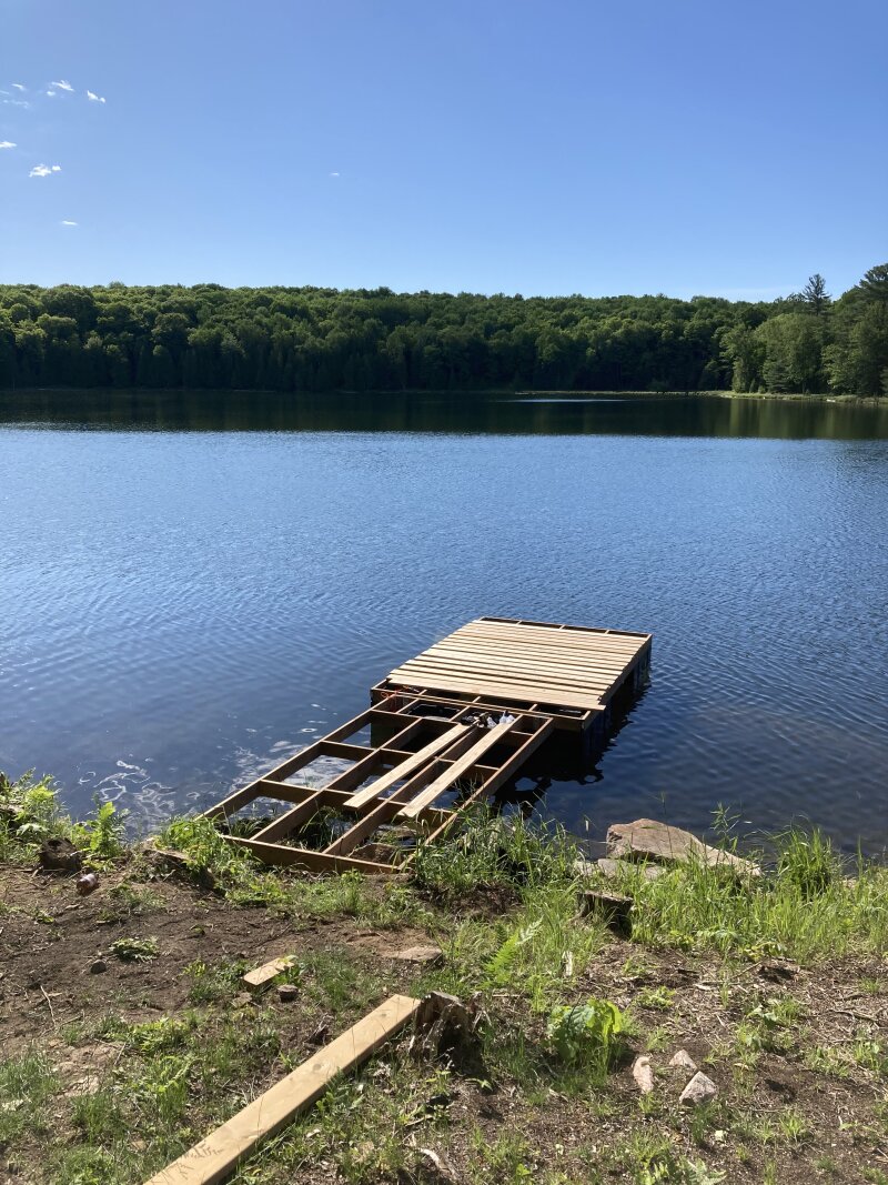 A half complete dock, missing decking and the last dock section, floating off shore.