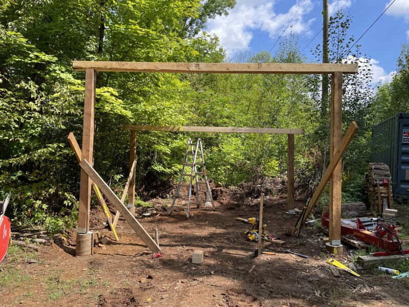 The frame of the structure standing, pre-rafters, braced square temporarily.