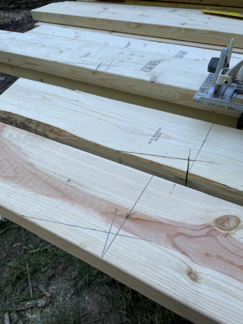 Multiple birds mouths marked out on rafters on saw horses, ready to be cut