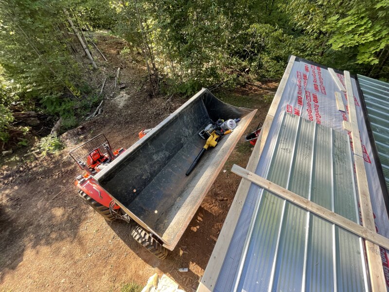 Standing on the roof looking down, the tractor bucket lifted to max height full of tools now within reach.
