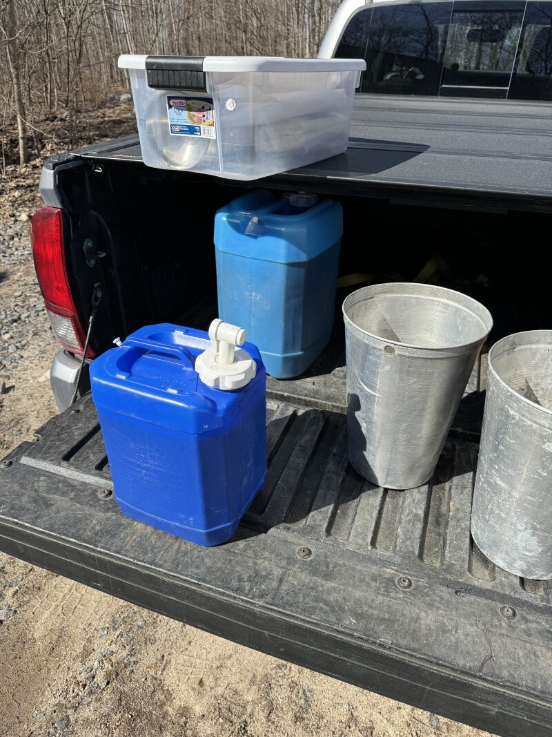 Various water tight containers on the truck tailgate, full of partially finished syrup