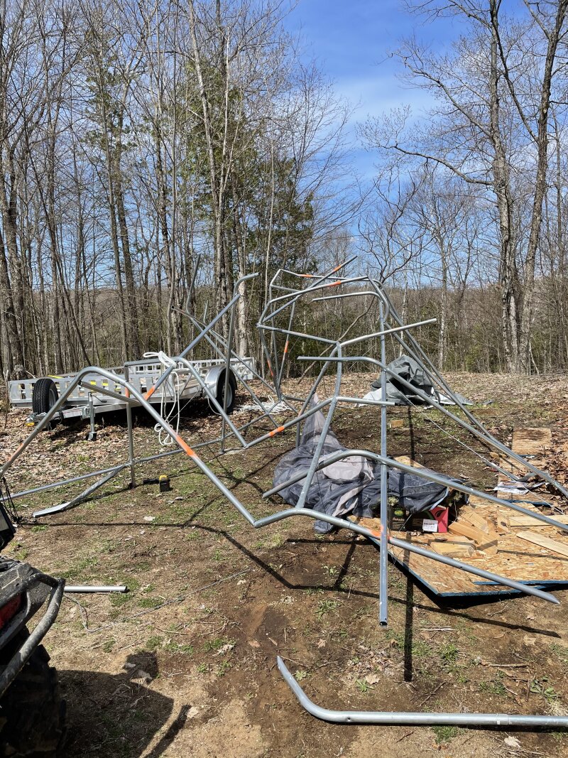 A 12 x 20 foot vinyl carport after being crushed with snow. The cover is removed and broken poles are marked for replacement
