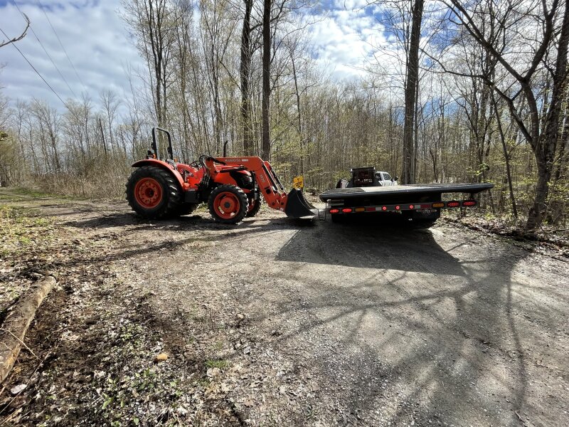A large truck and trailer on the road at the end of the driveway, stuck on a bend against a tree. My tractor sits beside it, staged to attempt to pull the trailer away from the tree.