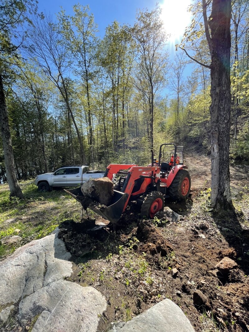 Down at the lakefront, the tractor bucket is lifting a large (roughly 2 foot cubed) boulder above a hole it had come from